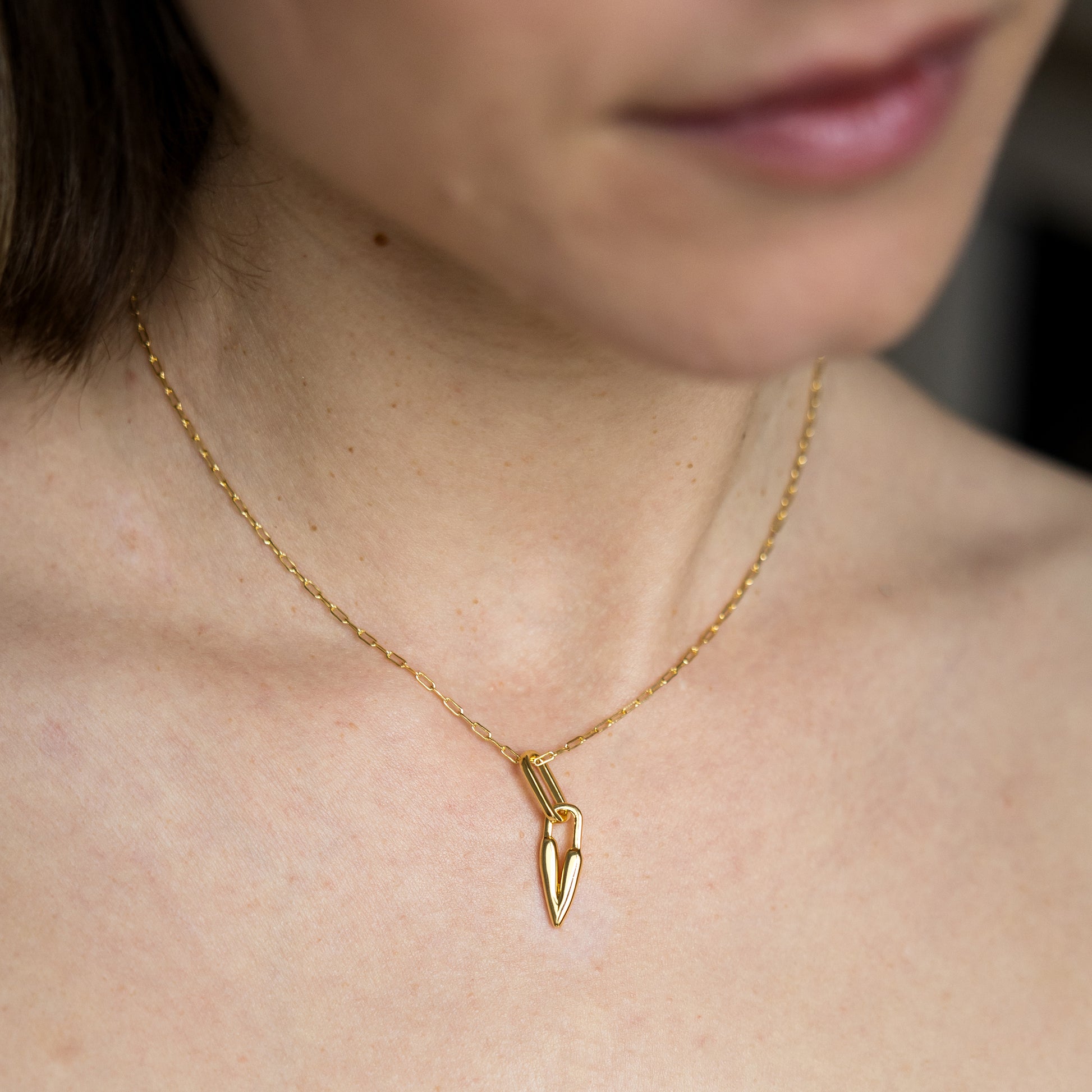 Gold necklace with a heart pendant worn by a person