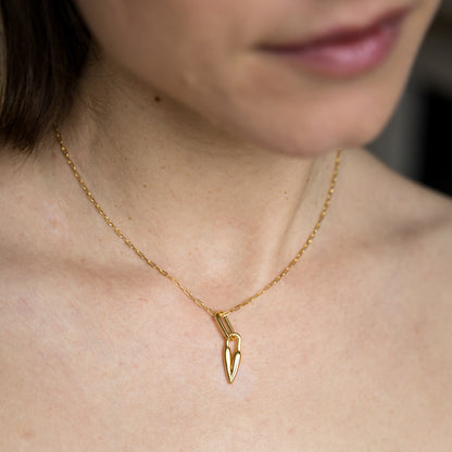 Gold necklace with a heart pendant worn by a person
