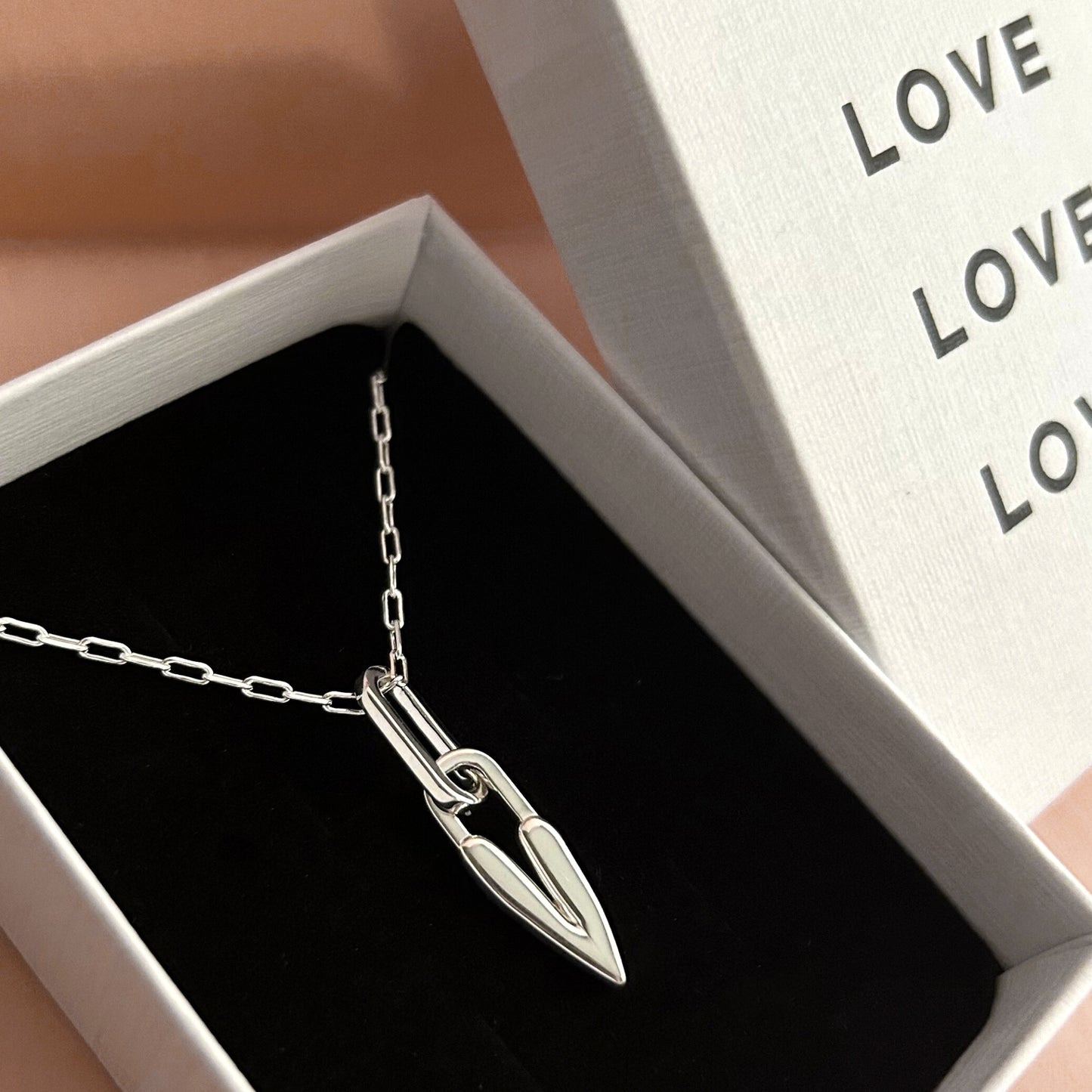Silver necklace with a heart pendant in an open jewelry box.