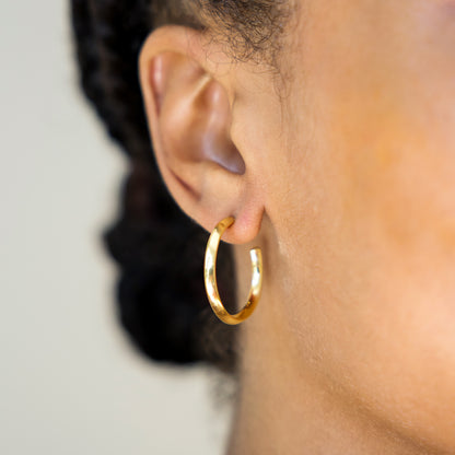 Gold hoop earring worn by a person with a blurred background