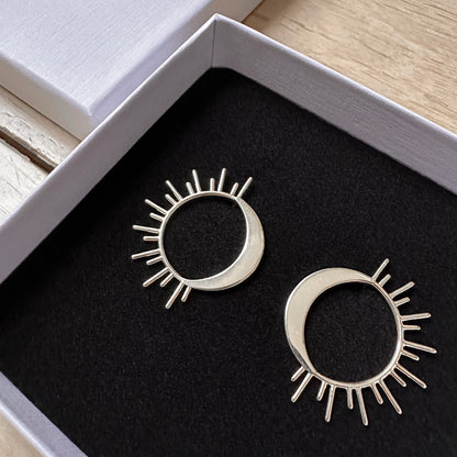 A pair of celestial sun and moon earrings in a box