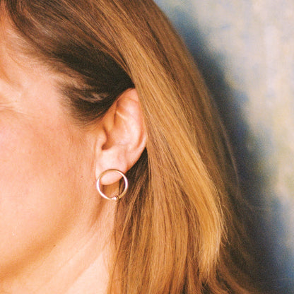 Close up of a person wearing a circular earring against a blurred background