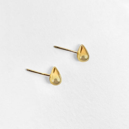 A pair of small gold water droplet stud earrings displayed against a white background.