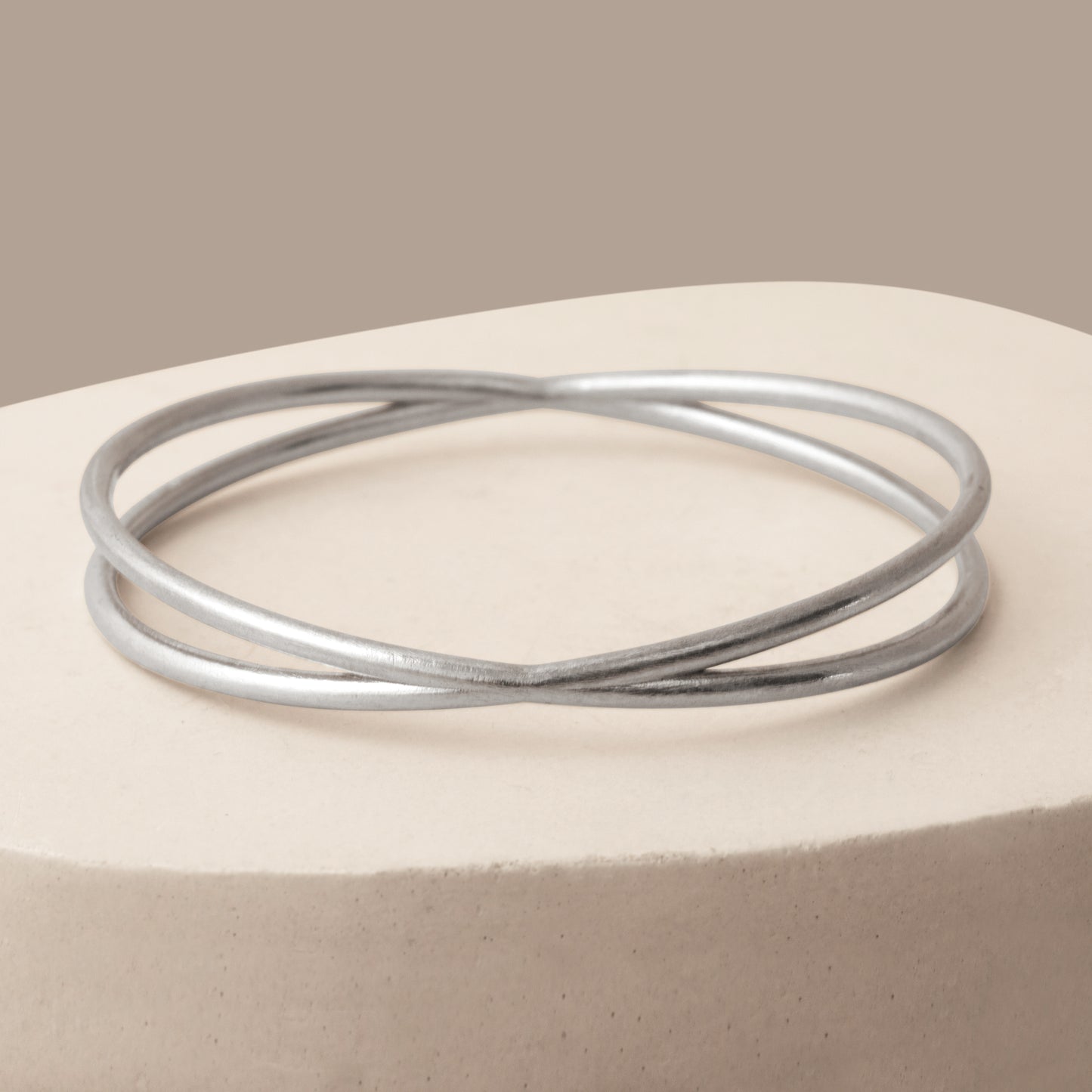 Close up of a silver bangle bracelet on a white stone background