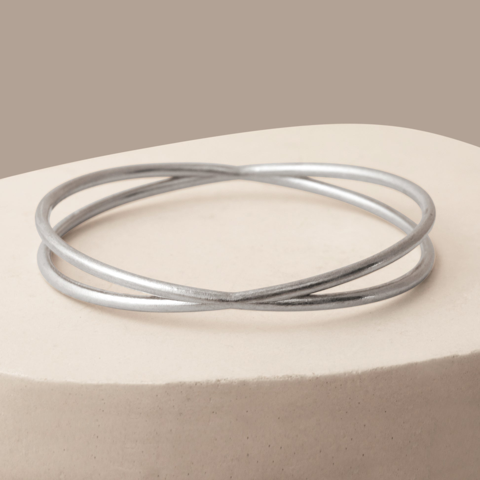 Close up of a silver bangle bracelet on a white stone background