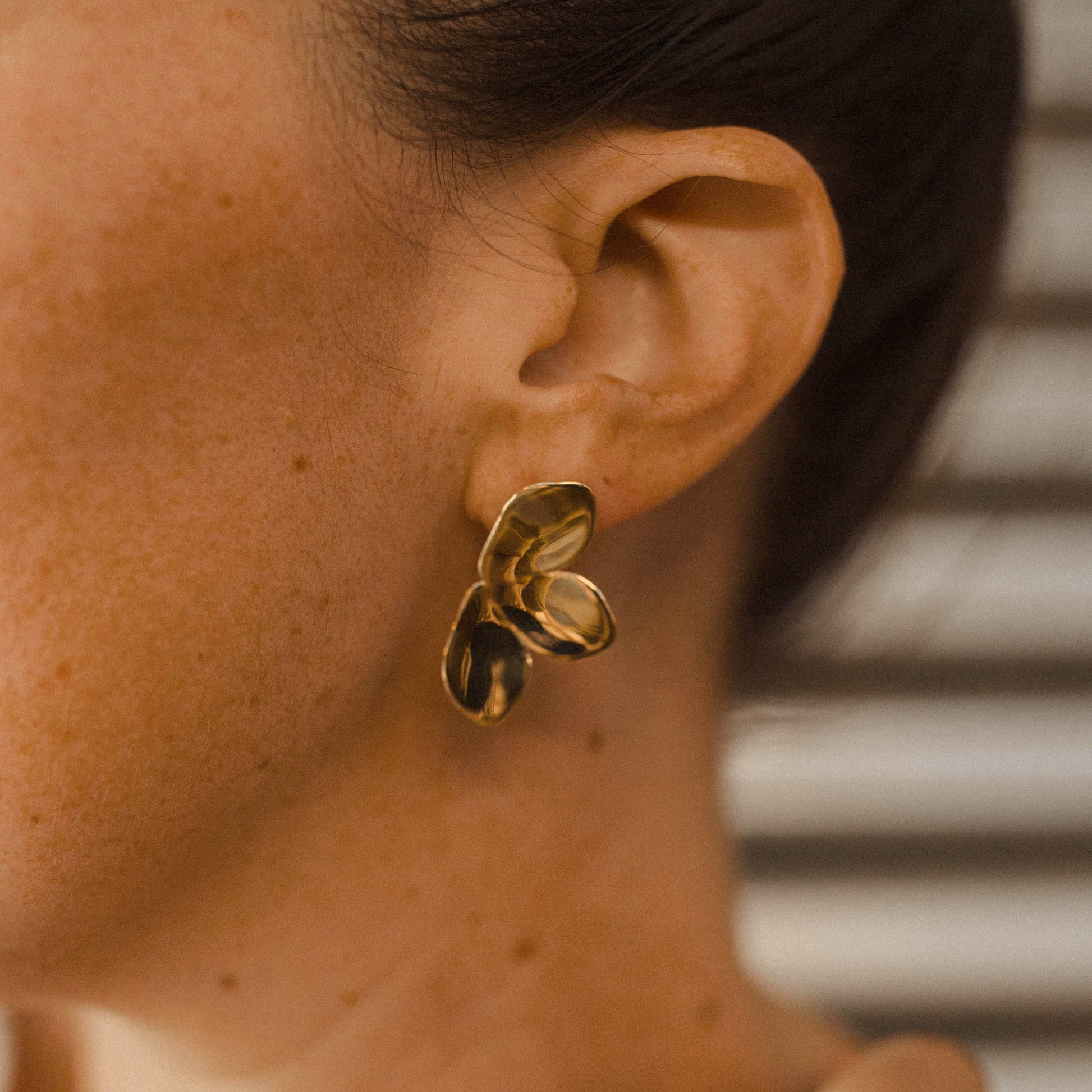 Close up of a person wearing a gold plant earring