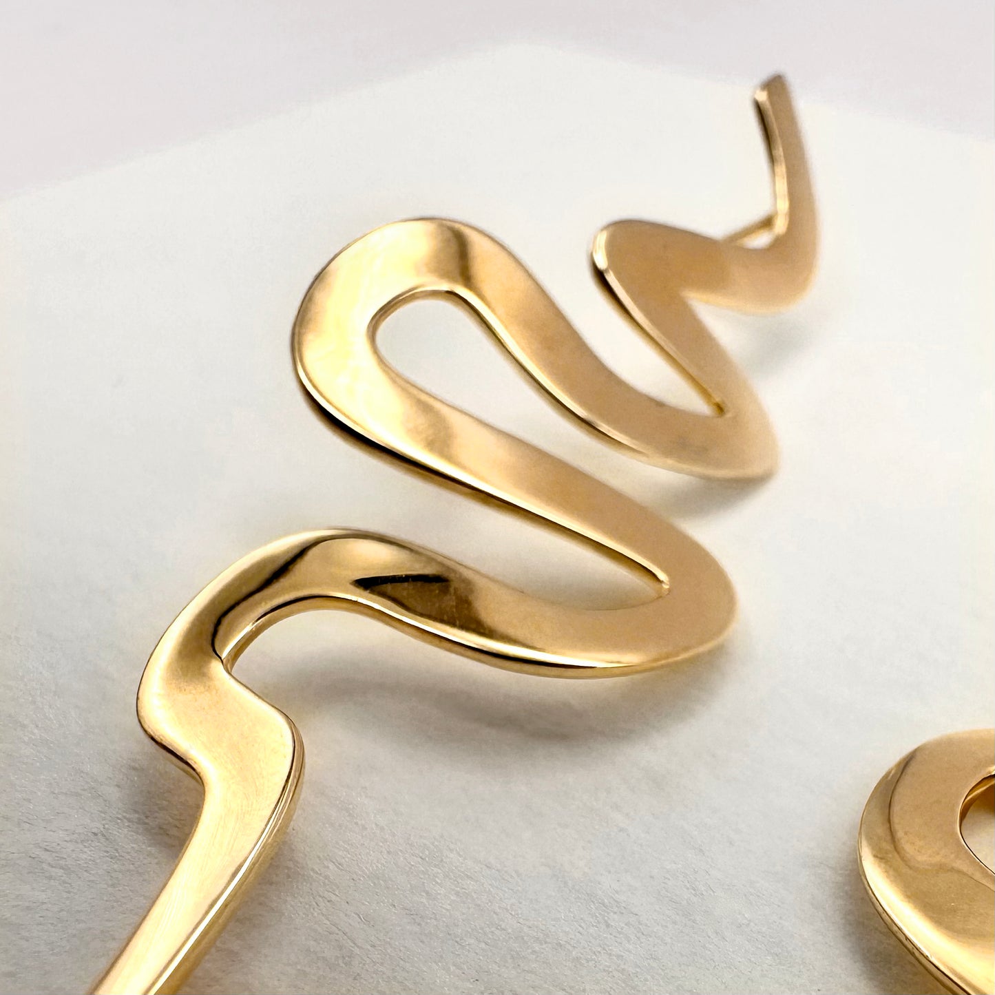 Close up of a ribbon Medusa earring on a white background