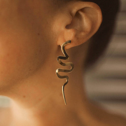 Close up of a person wearing a long snake-shaped Medusa earring