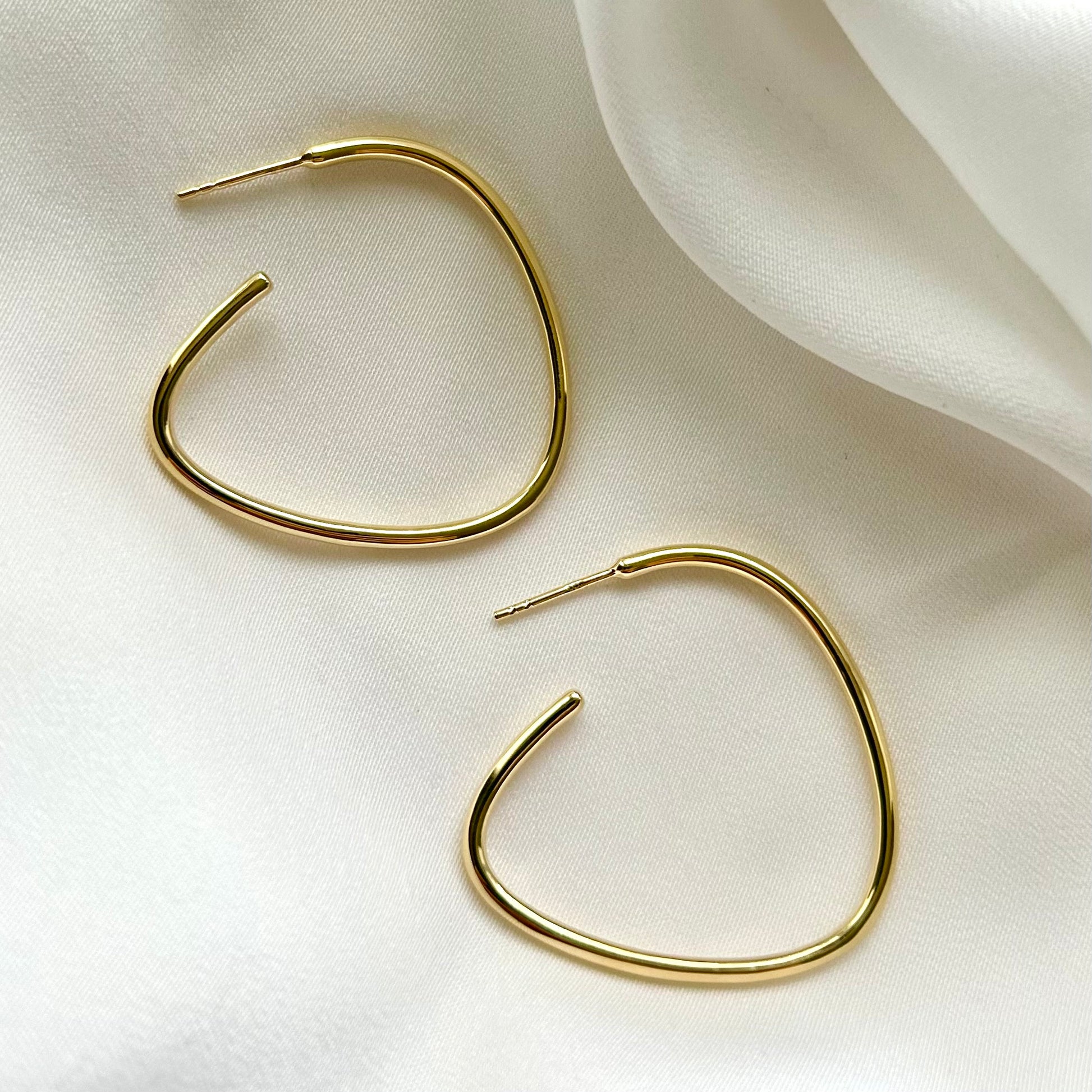 Gold hoop earrings on a light fabric background