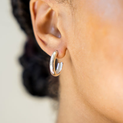 Silver hoop earring worn by a person with a blurred background