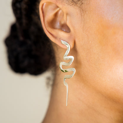 Silver spiral earring on a person's ear with a neutral background
