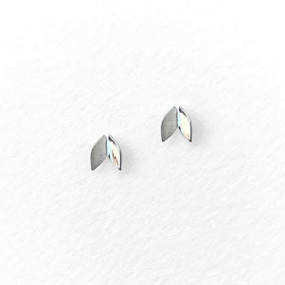 A pair of silver-colored leaf-shaped stud earrings against a white background.
