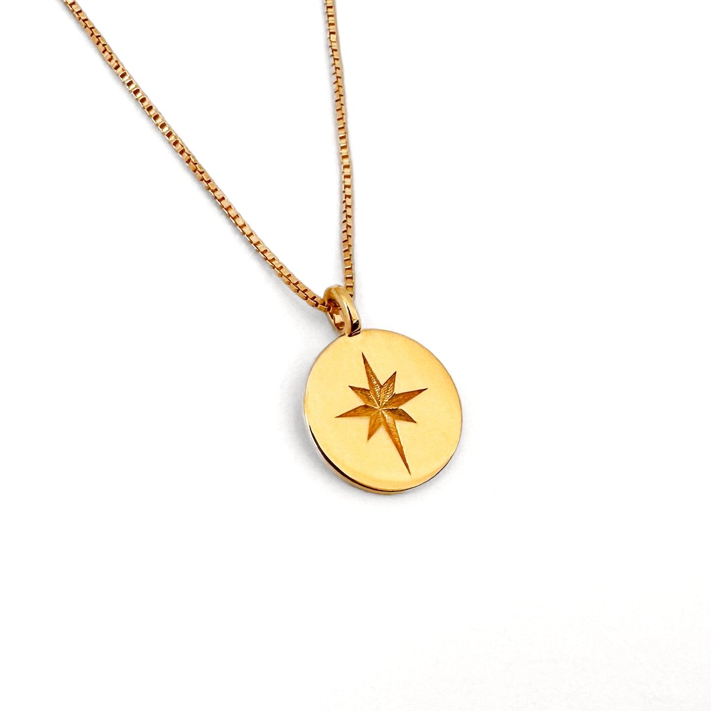A gold coin necklace with a star design in the center, displayed on a box chain against a white background.
