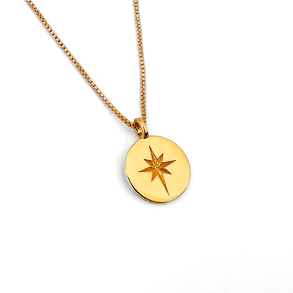 A gold coin necklace with a star design in the center, displayed on a box chain against a white background.