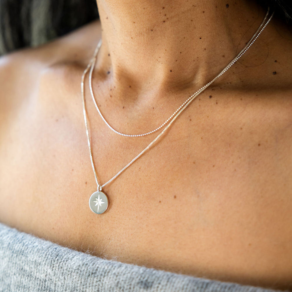 Close-up of a person wearing a silver necklace with a star pendant.