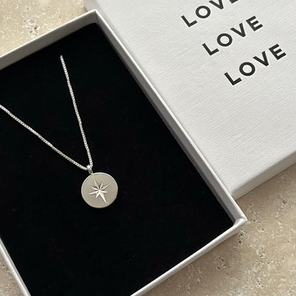 Silver necklace with a star pendant in a box labeled 'LOVE'.