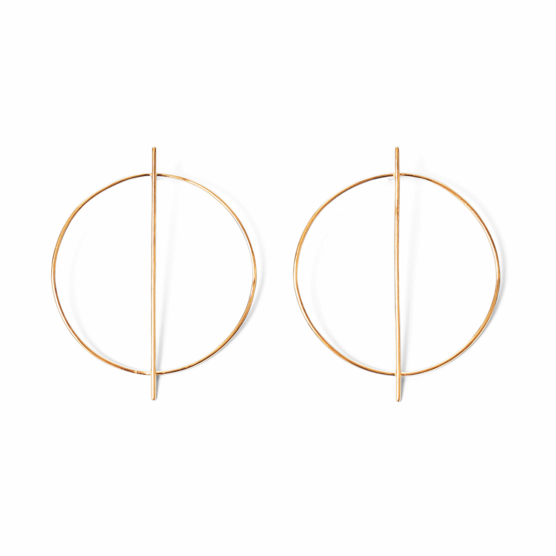 A pair of circular gold earrings with a line through them against a white background