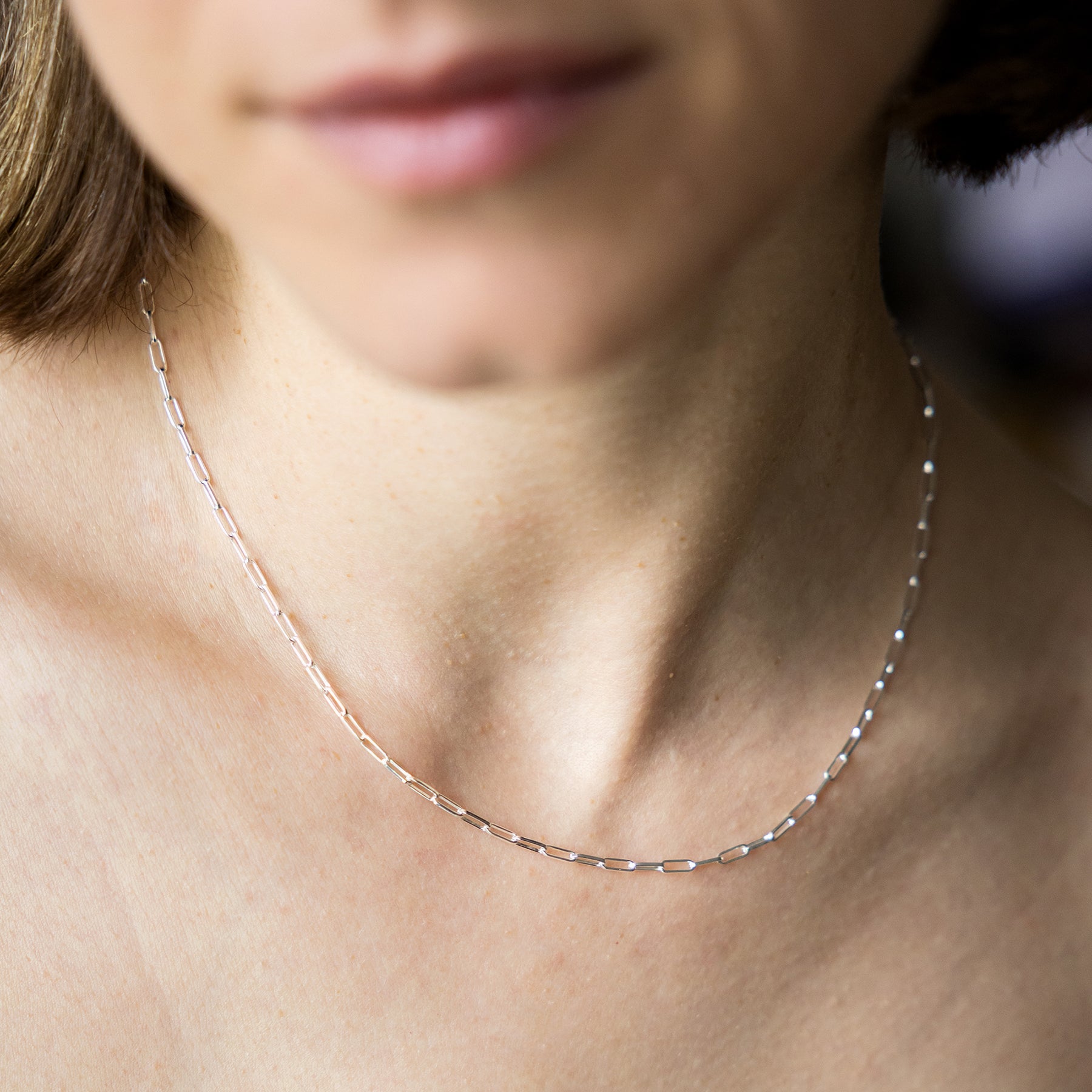 Close-up of a person wearing a delicate silver necklace.