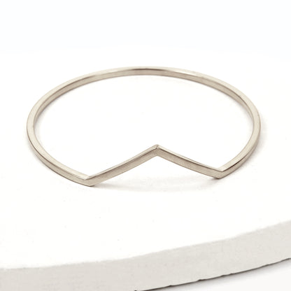 Silver bangle bracelet with triangle shaped V peak against a white background