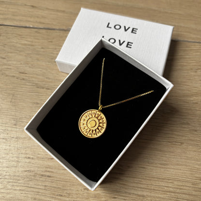 Gold necklace in a box with 'LOVE' text on a wooden surface