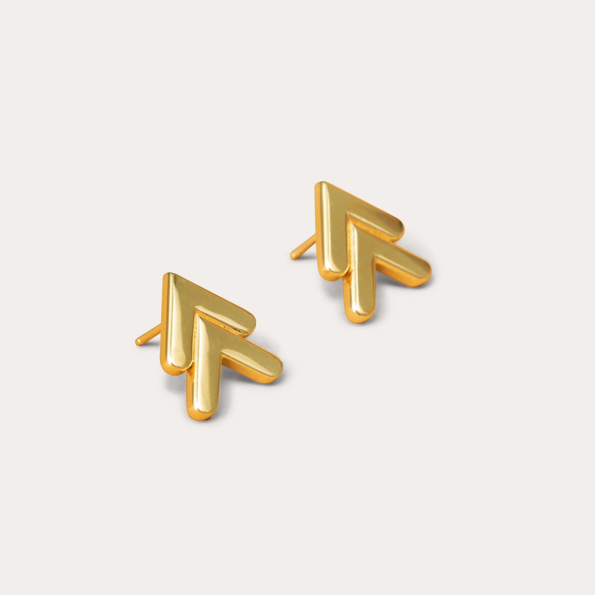 Pair of gold chevron stud earrings against a white background