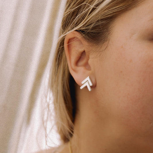 Close up of a person wearing a silver chevron stud earring