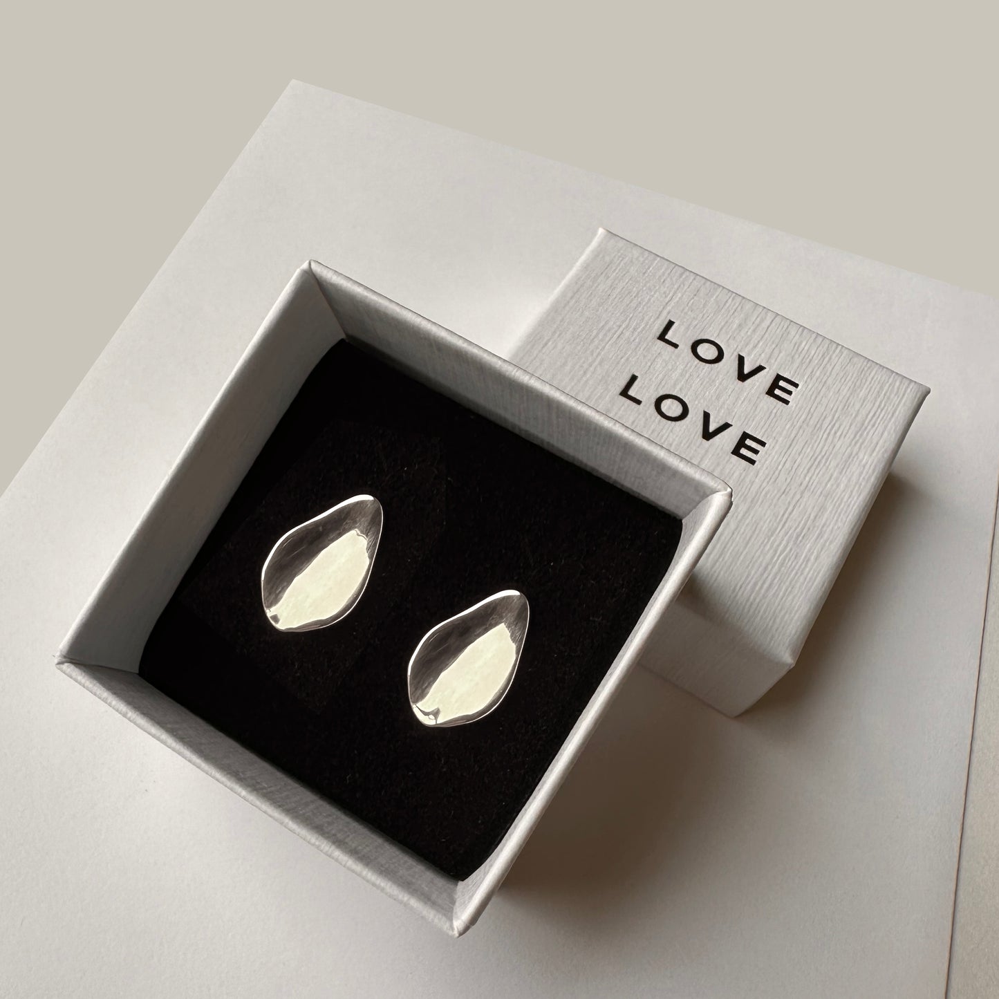 A pair of petal floral leaf earrings displayed in a box with the word 'LOVE' on it