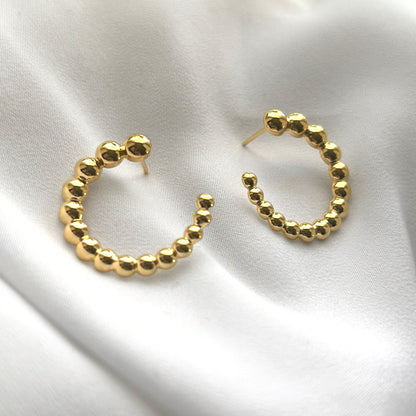 Gold hoop earrings on a white fabric background