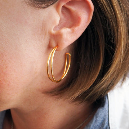 Gold hoop earrings worn by a person with short hair.