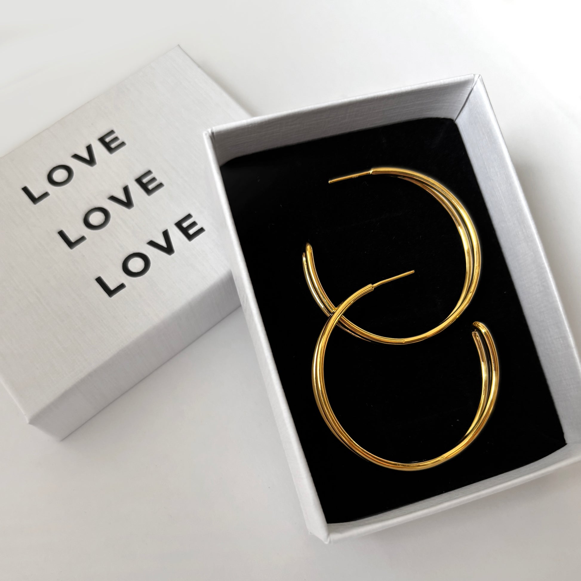 Gold earrings in a box with the word 'LOVE'.