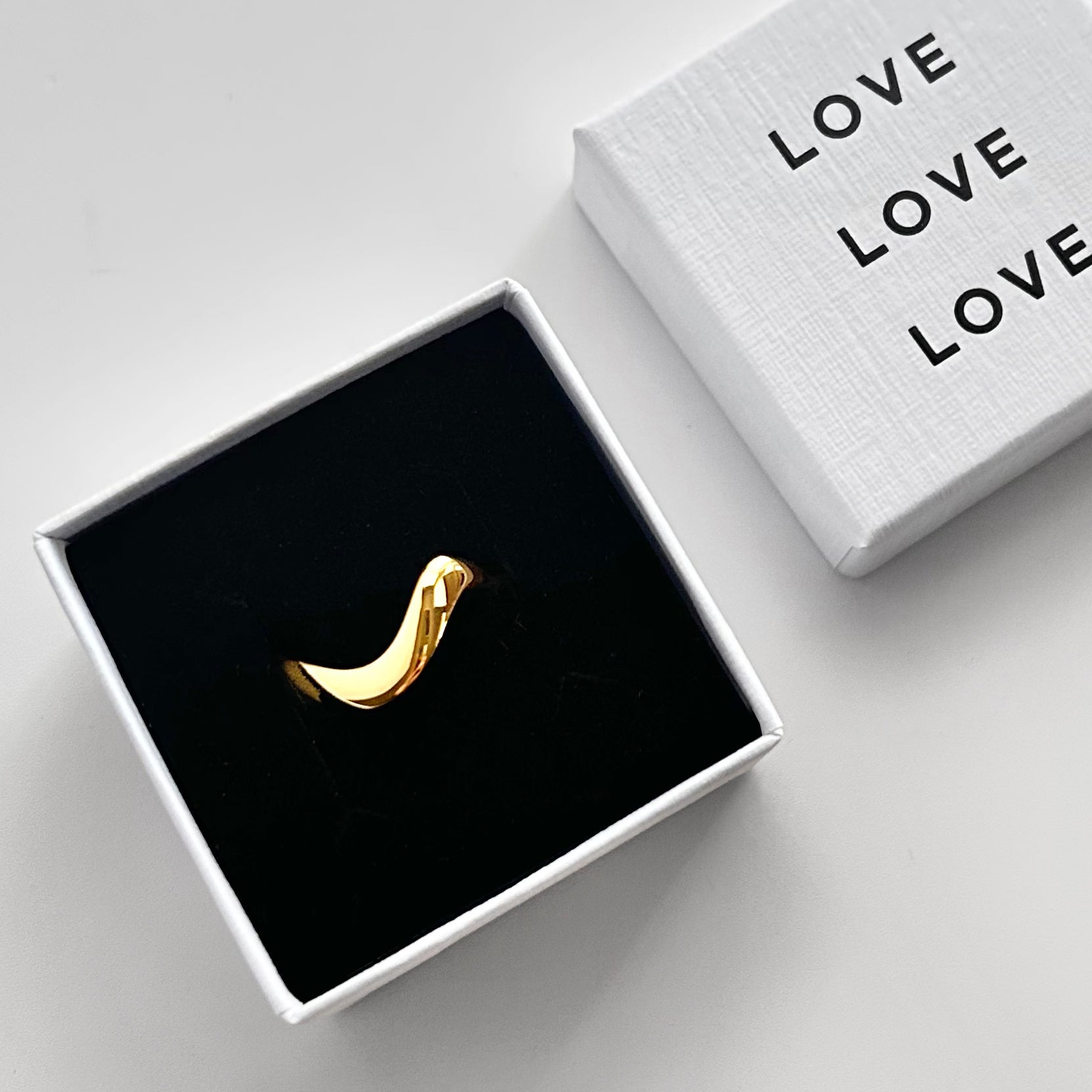 Gold ring in a black box with 'LOVE' text on a white background