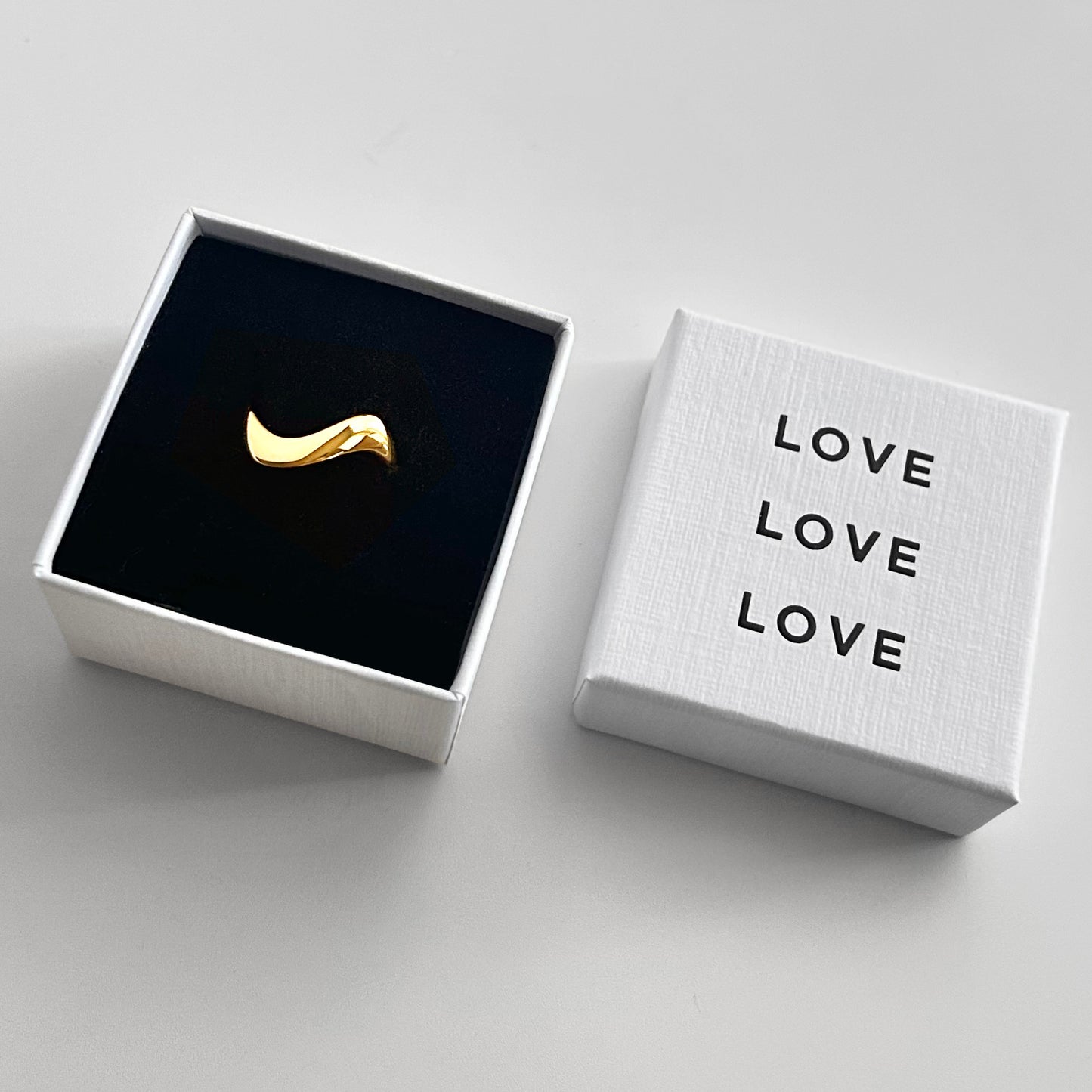 Gold ring in a black box with 'LOVE' text on a white background