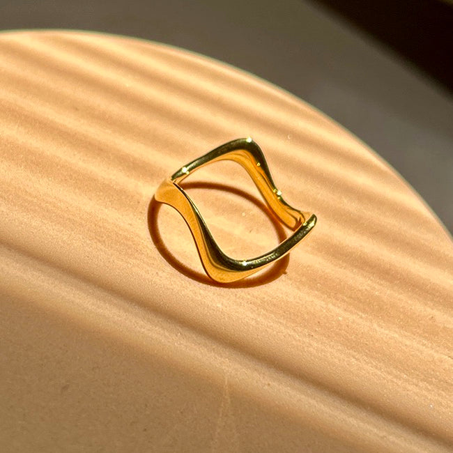 Gold ring on a beige surface with a soft shadow