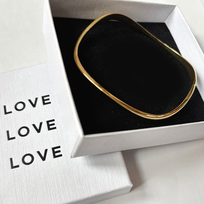 Gold bangle bracelet in a white box labeled 'LOVE'