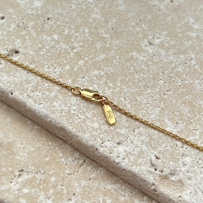Gold necklace with clasp on a textured beige surface