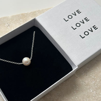 Pearl necklace in a box with 'LOVE' text