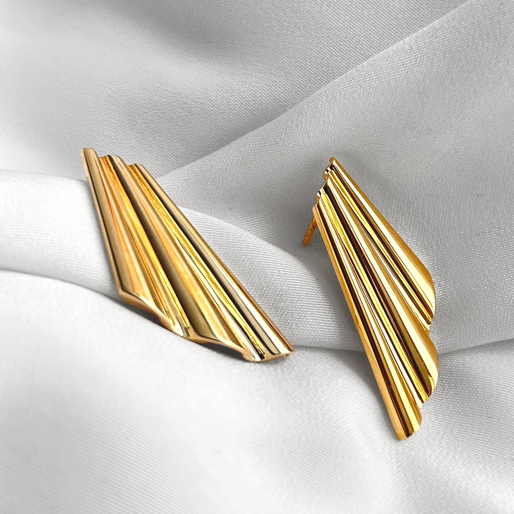 Gold shell earrings on a light fabric background