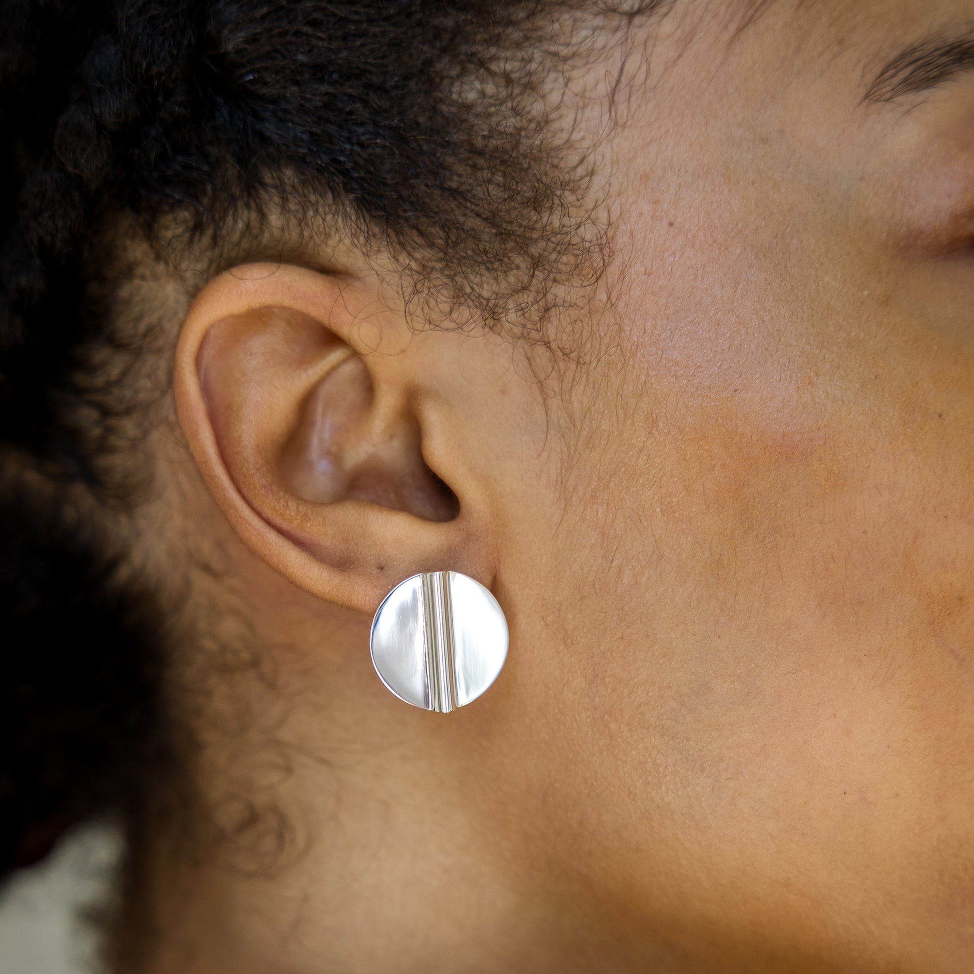 Close-up of an ear wearing a silver round earring.