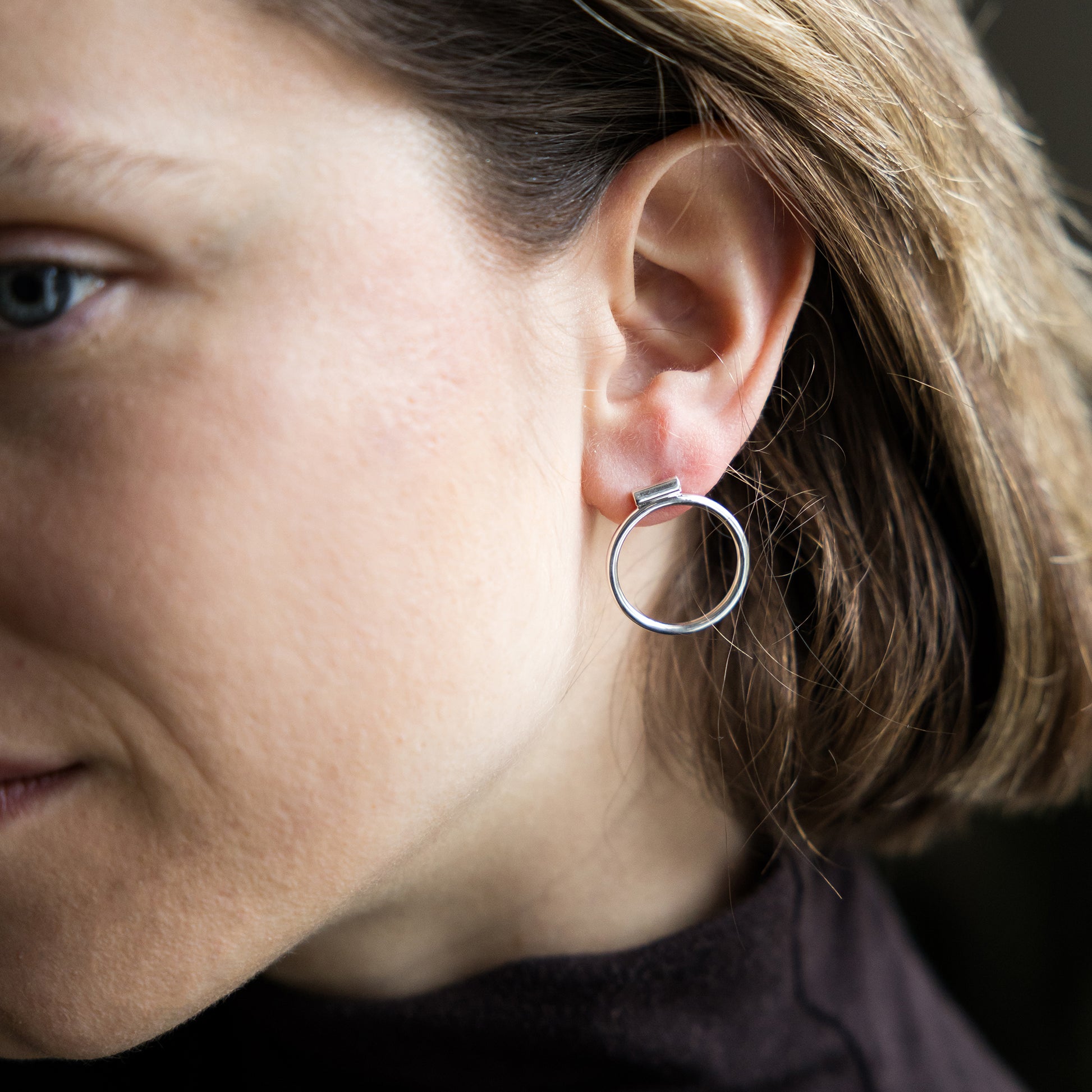 Close-up of a person wearing a silver hoop earring.