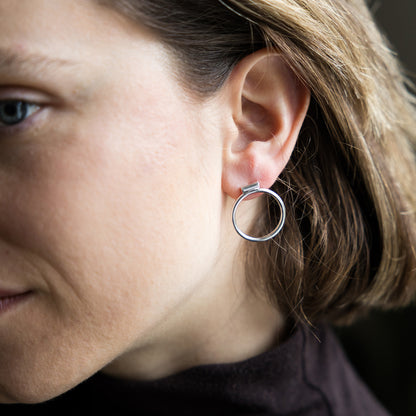 Close-up of a person wearing a silver hoop earring.