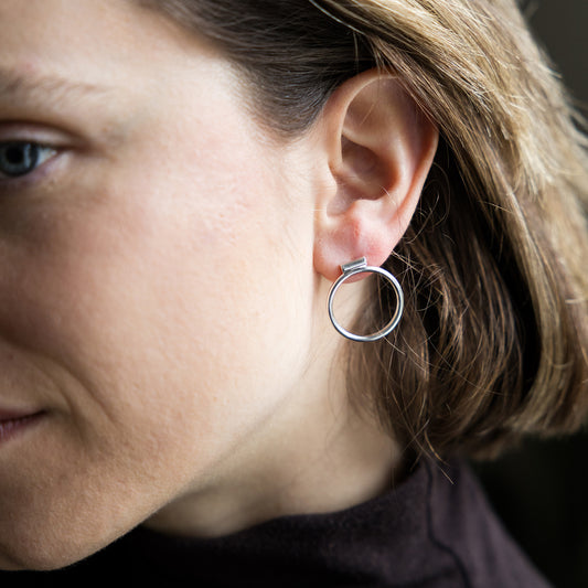 Close-up of a person wearing a silver hoop earring.