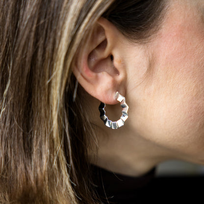 Close-up of a person wearing a silver hoop earring with a blurred background