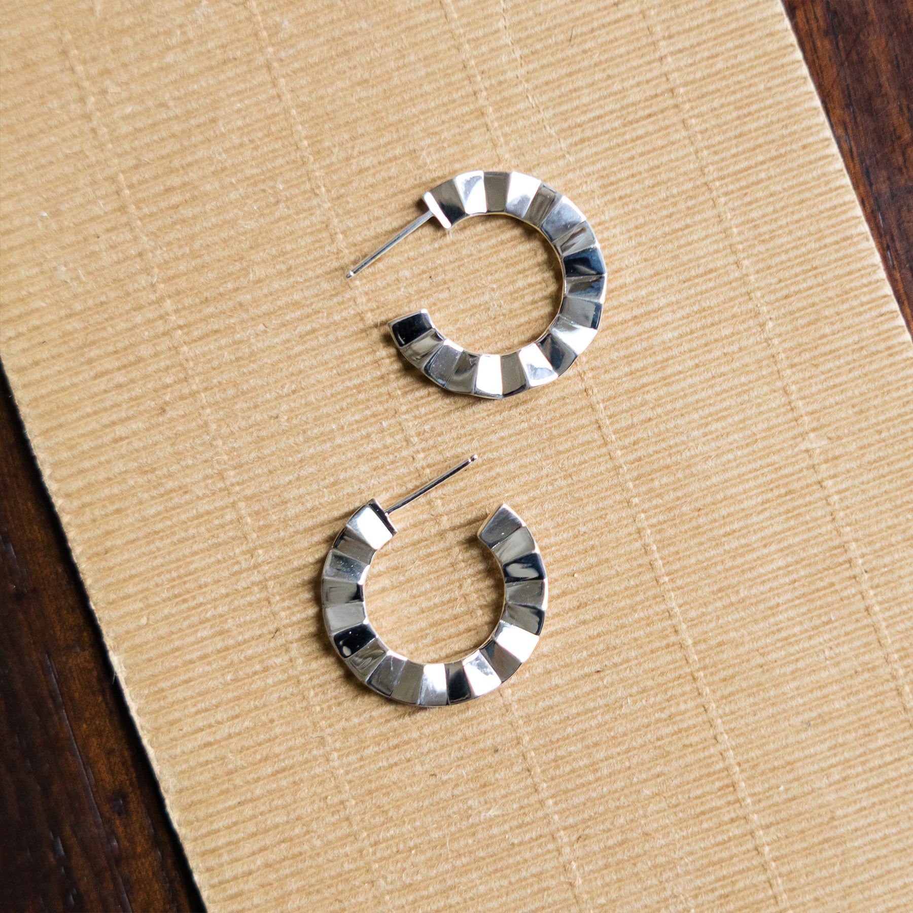 Silver hoop earrings on a beige surface
