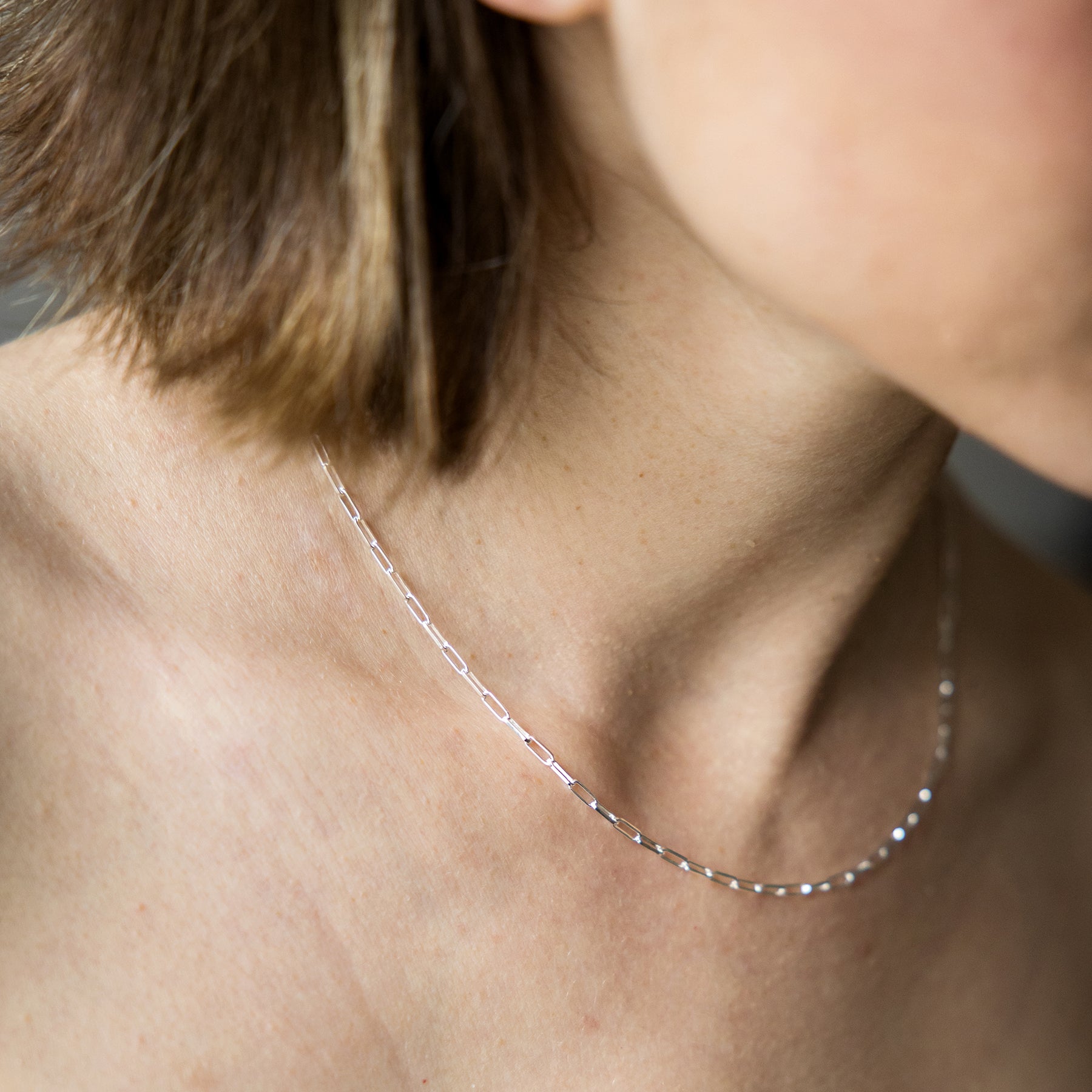 Close-up of a person wearing a delicate silver necklace.