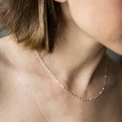 Close-up of a person wearing a delicate silver necklace.