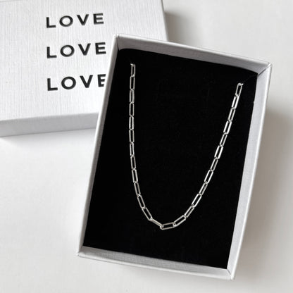 Silver necklace in a box with 'LOVE' text on a white background