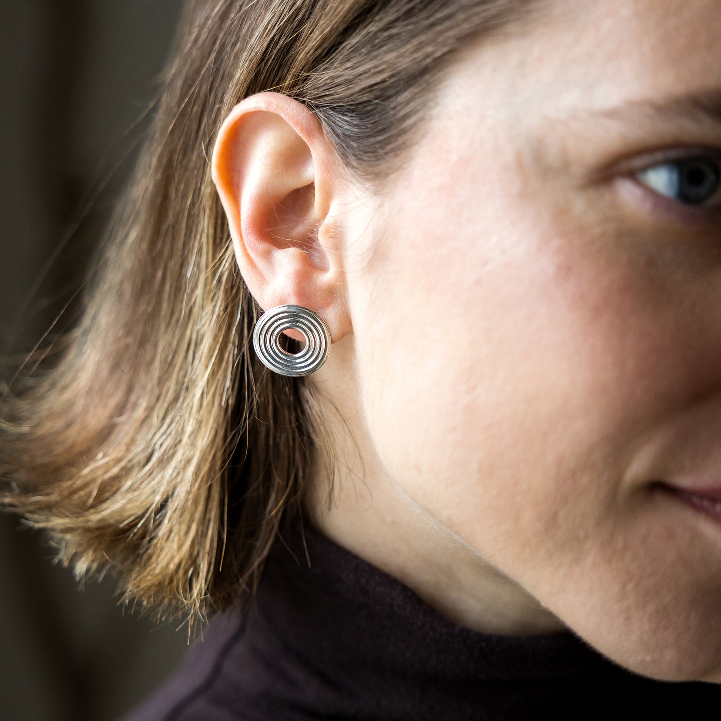 Close-up of a person wearing a silver spiral earring.