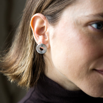 Close-up of a person wearing a silver spiral earring.
