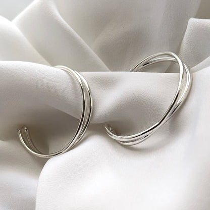 Silver hoop earrings on a white fabric background