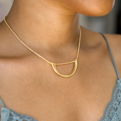 Gold necklace with a unique pendant worn by a person